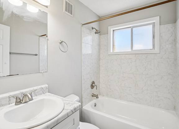 A white bathroom with a sink, toilet, and bathtub.