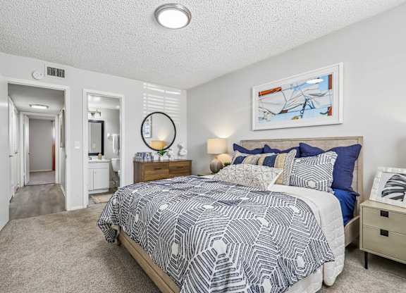 A bedroom with a bed, nightstand, and a painting on the wall.