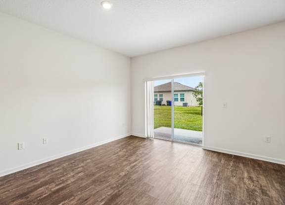 A room with a sliding glass door leading to a backyard.