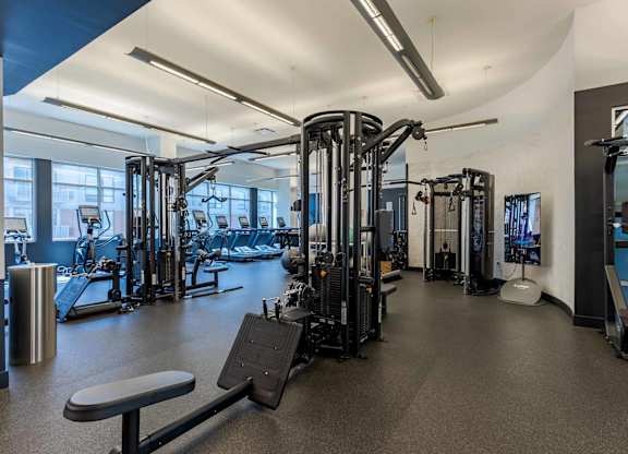 A gym with a variety of equipment including treadmills, weights, and exercise machines.