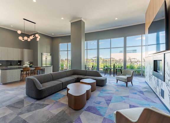 A modern living room with a grey sofa and a kitchen area in the background.