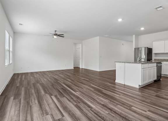 A room with a kitchen island and wooden floors.