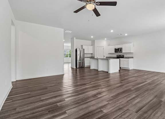 A room with a ceiling fan and wooden flooring.