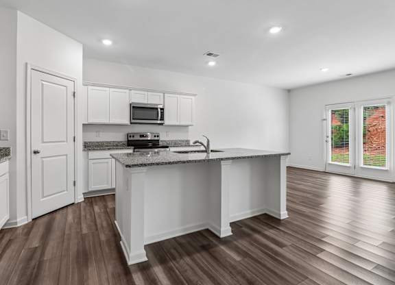 A kitchen with white cabinets and a wooden floor.
