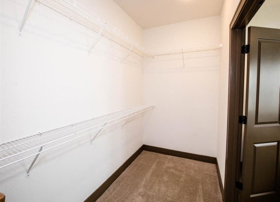 a walk in closet with a white wall and a closet door