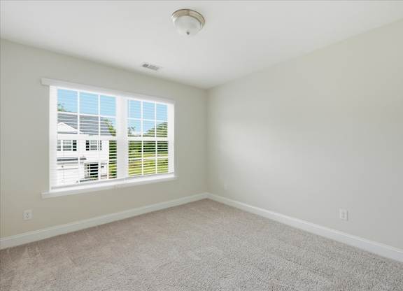A room with a window and a carpeted floor.