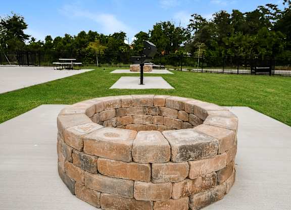 A stone fire pit sits in the middle of a concrete patio.