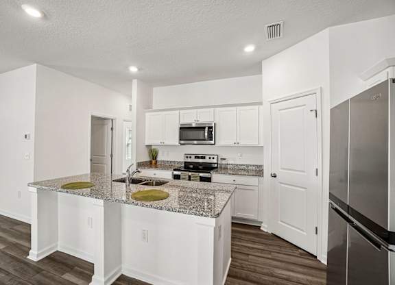 A kitchen with white cabinets and a granite countertop.