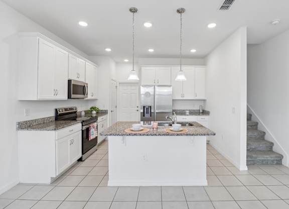 A kitchen with white cabinets and a granite countertop.