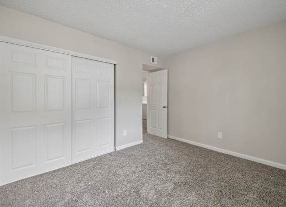 A room with a white door and carpeted floor.