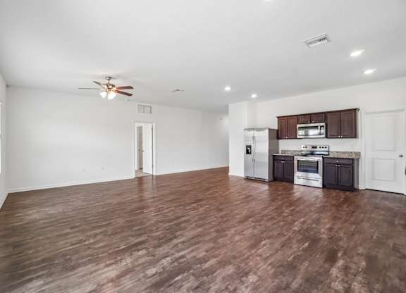 A spacious room with a kitchen area and wooden flooring.