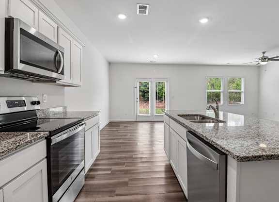 A modern kitchen with a dark wood floor and white cabinetry.