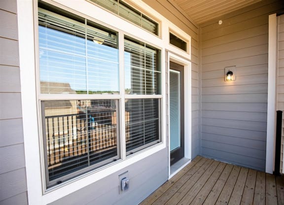 the deck of a home with large windows and a door
