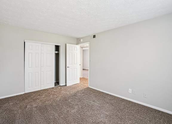 A room with two white doors and carpeted floor.