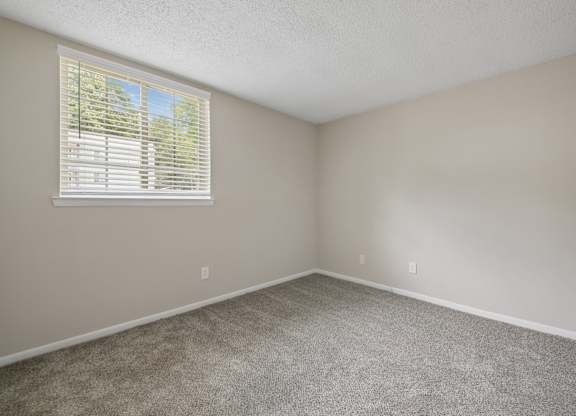A room with a window covered by white blinds.