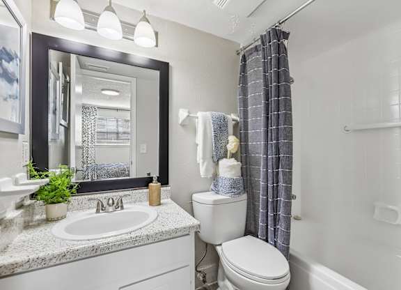 A bathroom with a white toilet, sink, and shower area.