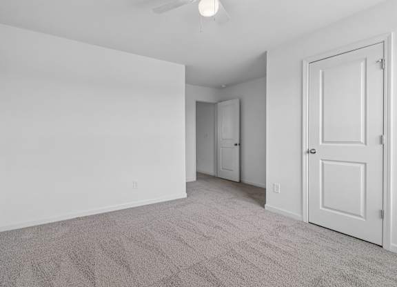 A room with a carpeted floor and a ceiling fan.