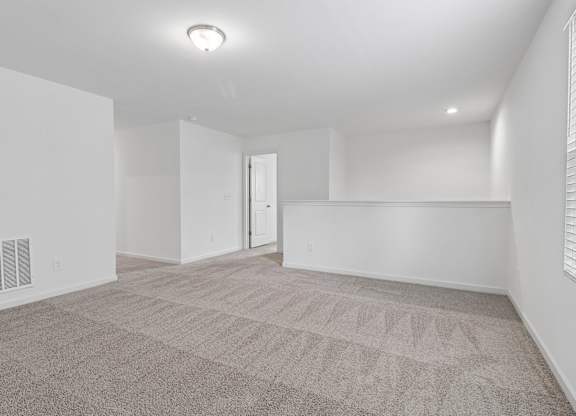 A spacious room with a carpeted floor and a door in the background.