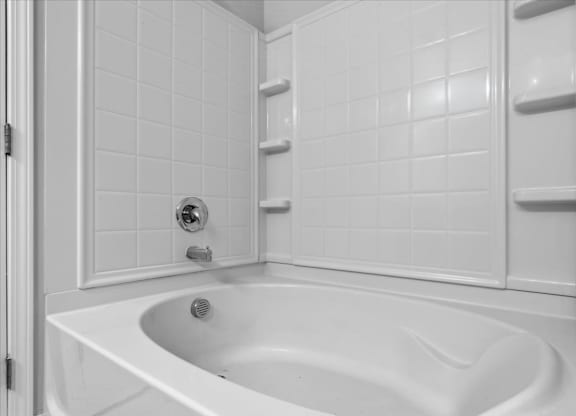 A white bathroom with a white tub and white tiles.