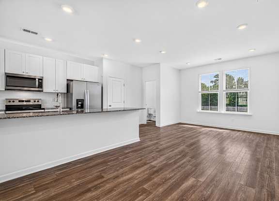 A kitchen with white cabinets and a wooden floor.