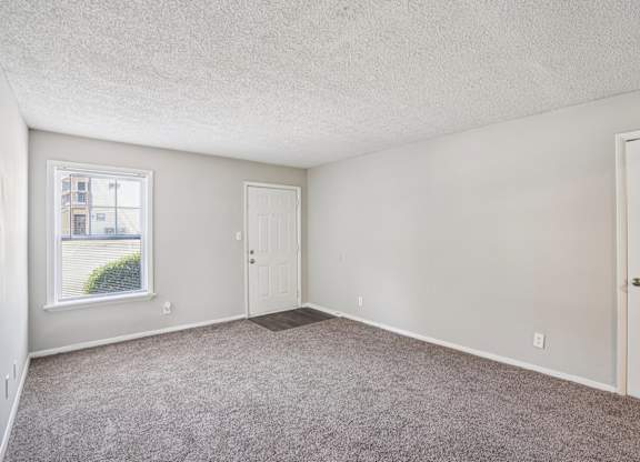 A room with a carpeted floor and two doors.