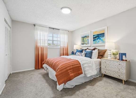 A bedroom with a bed, nightstand, and a window with curtains.