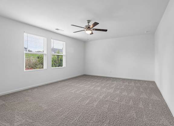 A room with a ceiling fan and carpeted floor.