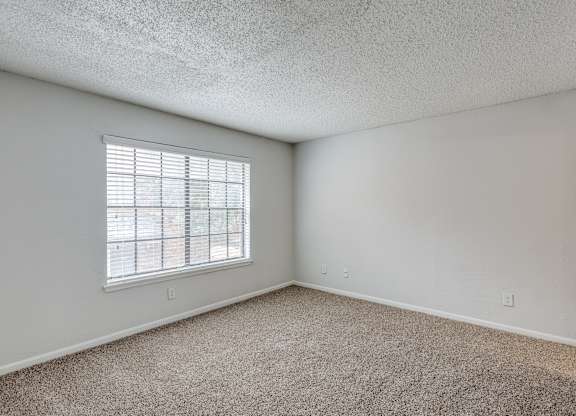 A room with a window and carpeted floor.