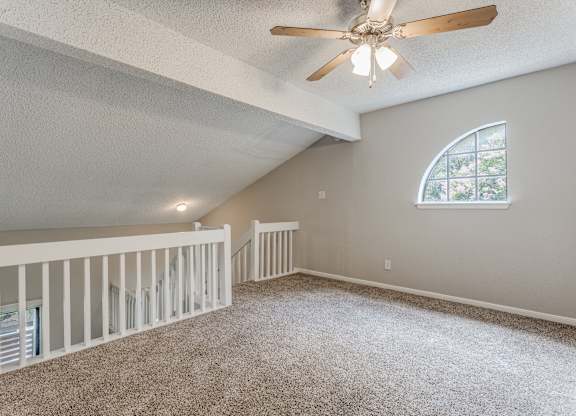 a large lofted bedroom with carpeted flooring and a ceiling fan
