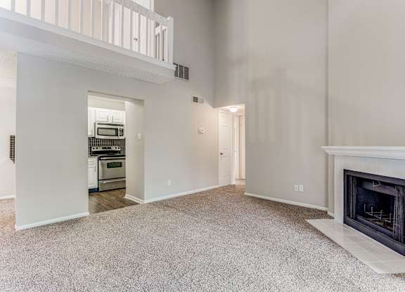 a living room with a fireplace and a kitchen in the background