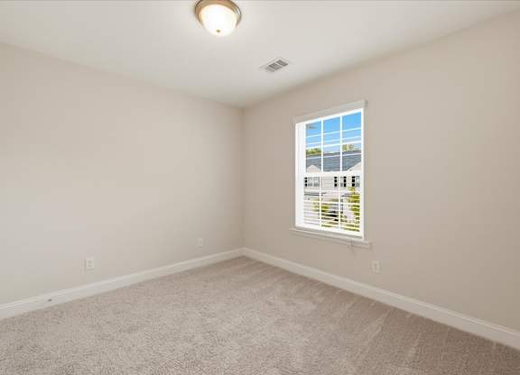 A room with a carpeted floor and a window with blinds.