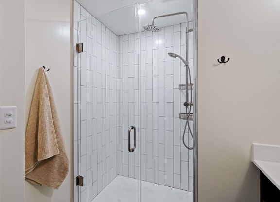 a white tiled shower with a glass door in a bathroom