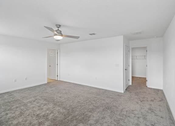A room with a ceiling fan and carpeted floor.