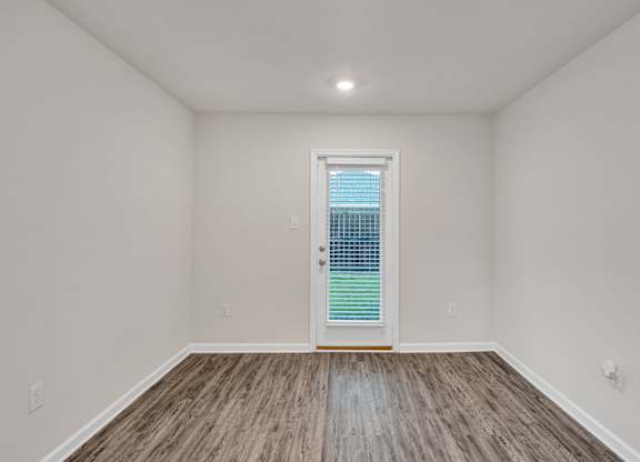 A room with a window and wooden flooring.