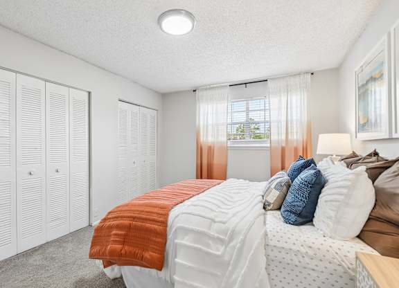 A bedroom with a bed, pillows, and a window with curtains.