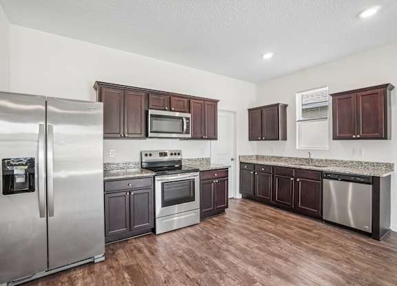 A kitchen with a refrigerator, microwave, oven, and dishwasher.