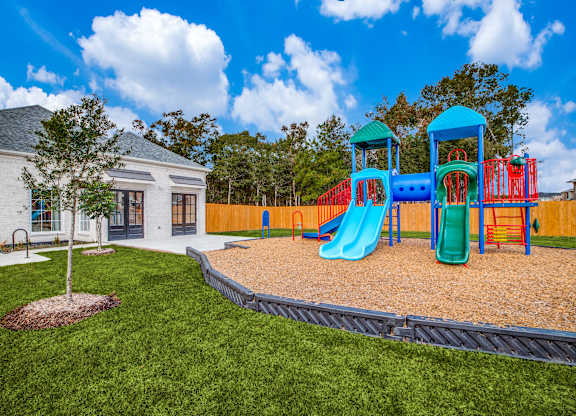 Dog-Friendly Homes for Rent in Humble, TX - Edgewater at the Lagoon - Playground with Slides, Climbing Areas, Woodchips, Well-Maintained Grass, and Surrounding Fence