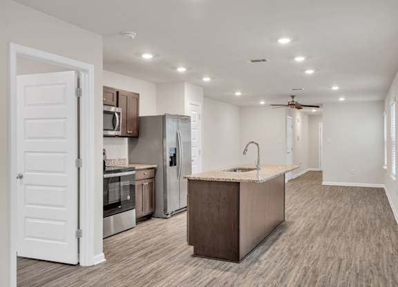 A kitchen with a refrigerator, oven, and sink.