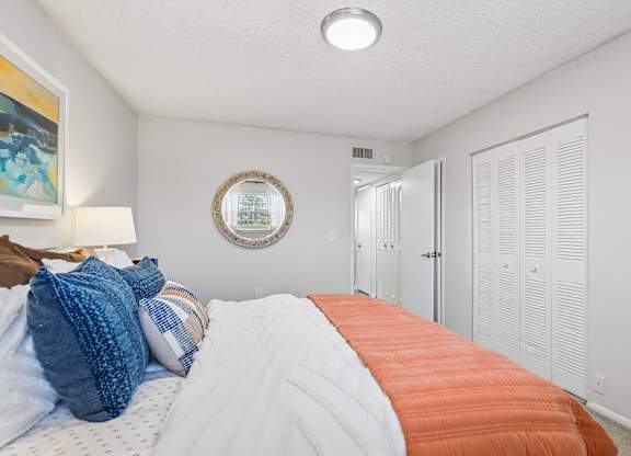 A bedroom with a bed covered in a white and orange comforter.
