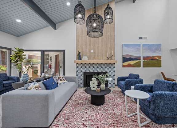 A living room with a grey couch, blue chairs, and a fireplace.