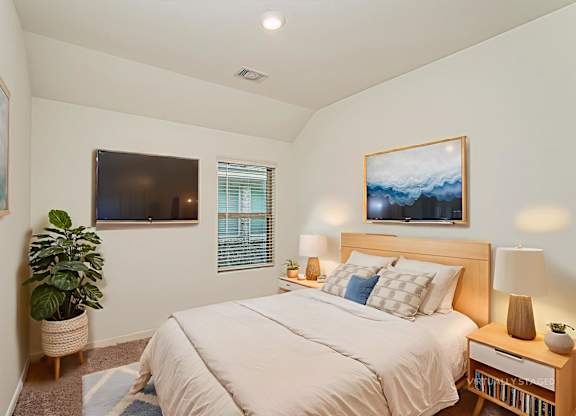 A bedroom with a bed, nightstand, and a painting on the wall.