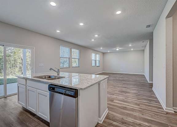 Open concept kitchen and living area with wood-look flooring, granite countertops, and stainless steel appliances.