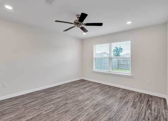 A room with a ceiling fan and a window with blinds.