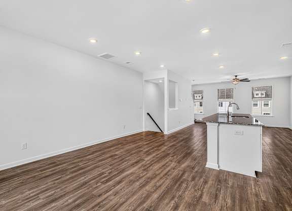 A room with a kitchen island and wood flooring.
