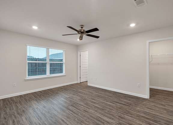 A room with a ceiling fan and a window with blinds.