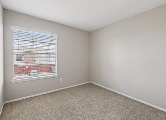 A room with a window and a view of a red building outside.