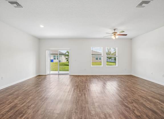 Empty room with wood flooring and a ceiling fan.
