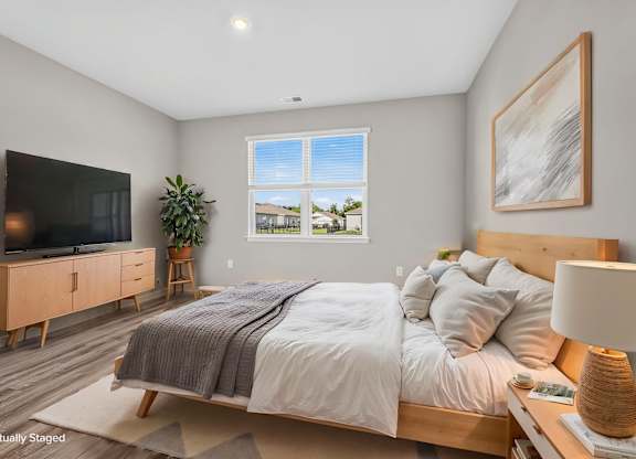 A bedroom with a large bed, a television, and a window with a view of the outdoors.