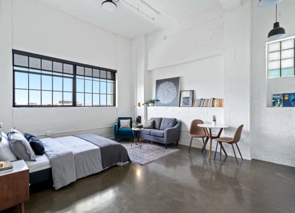 a bedroom with a bed and a living room with a table and chairs