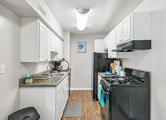 A kitchen with black appliances and white cabinets.